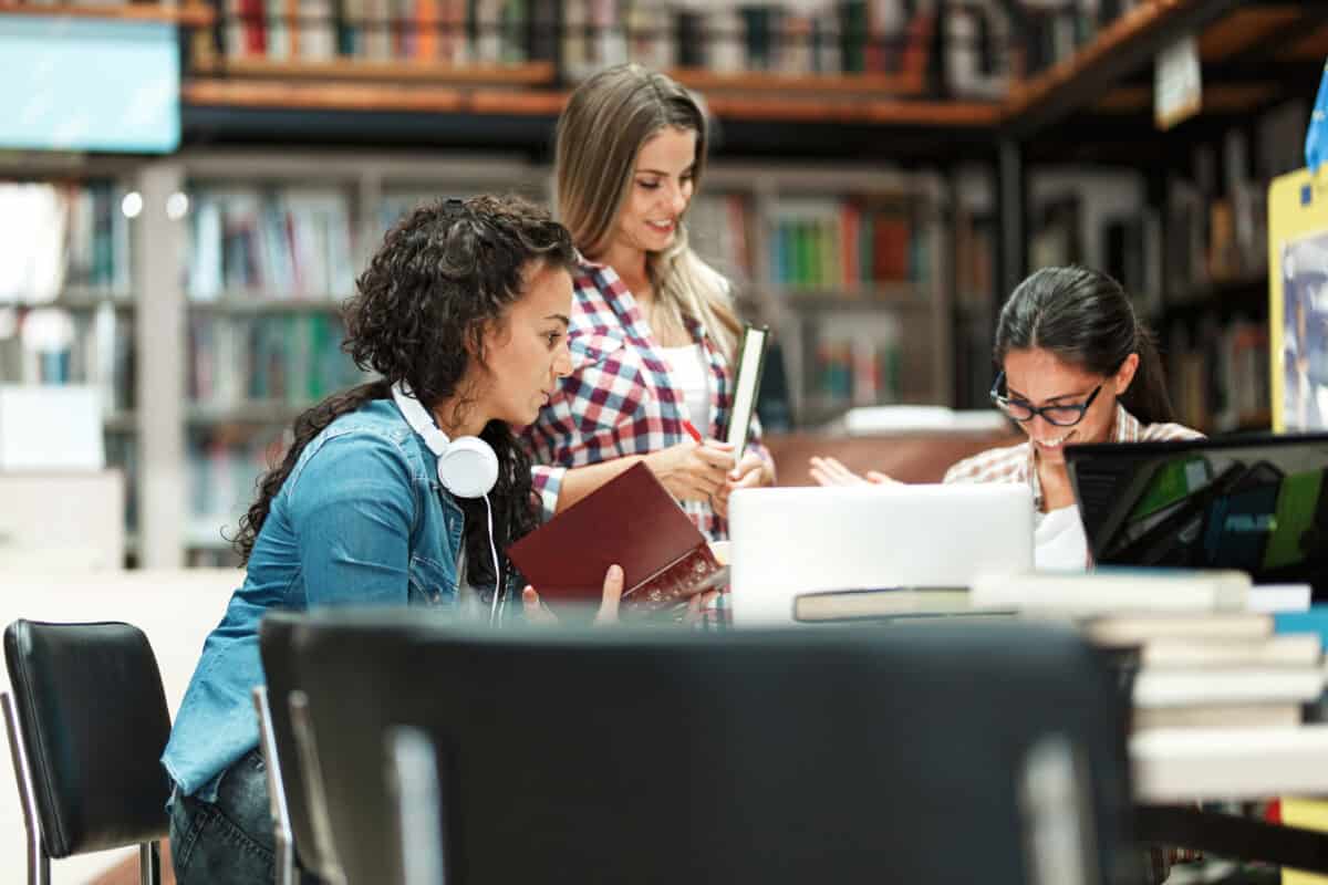 A group of driven female students occupies a corner of the campus library, immersed in their studies, determined to succeed in their upcoming exams.