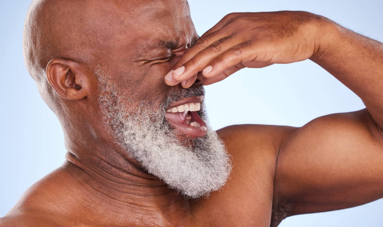 A man pincing his nose closed making a face.